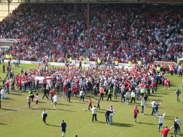 Town fans mob the players in a pitch invasion - the point against Walsall enough to seal promotion.